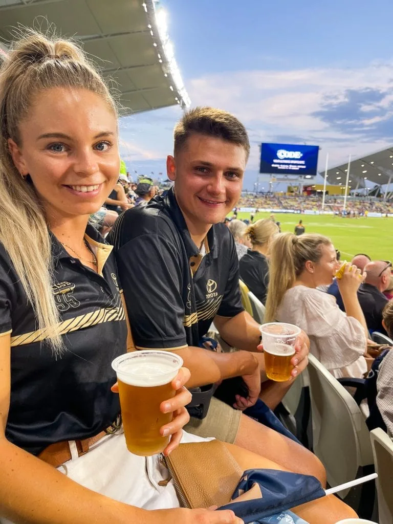 A male and female holding a beer watching a game at Townsville Stadium