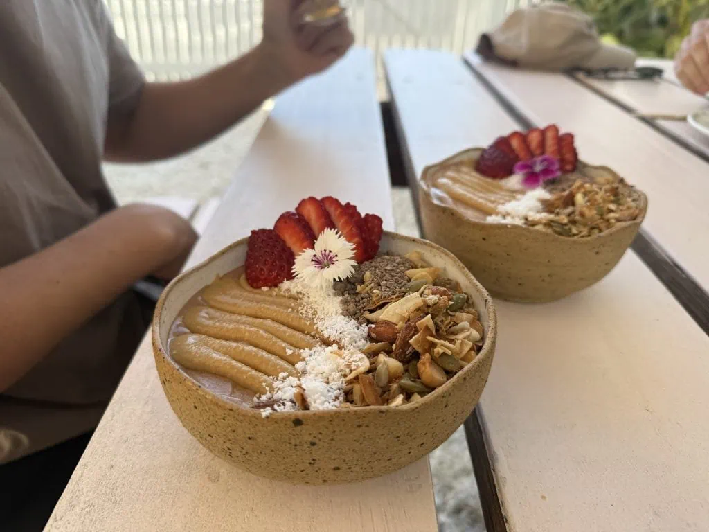 Two smoothies bowls with toppings such as granola, peanut butter and coconut