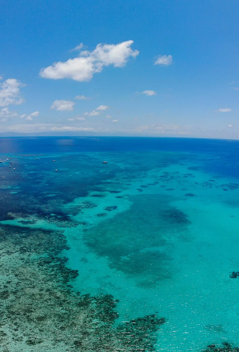 different shades of blue coloured water and coral reef from above on a scenic flight